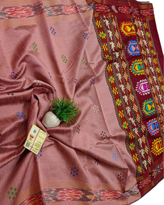 A dusty rose pink silk saree with a wide, richly patterned maroon border. The border features colorful geometric and floral motifs in red, yellow, blue, green, and white.