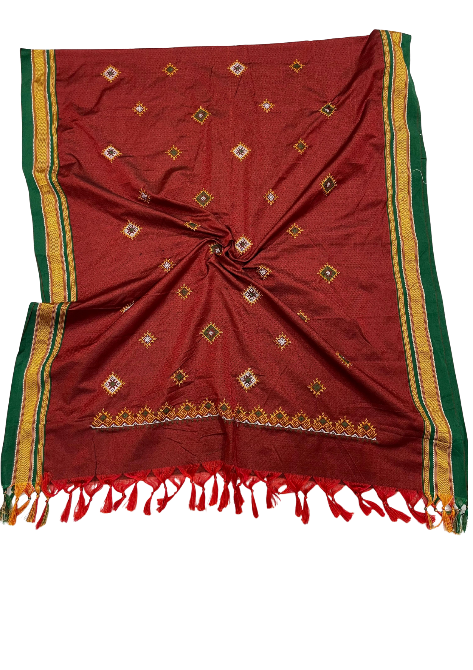 A red silk saree or scarf with green and gold borders, decorated with small diamond motifs and red tassels along the edge, laid flat on a white background.