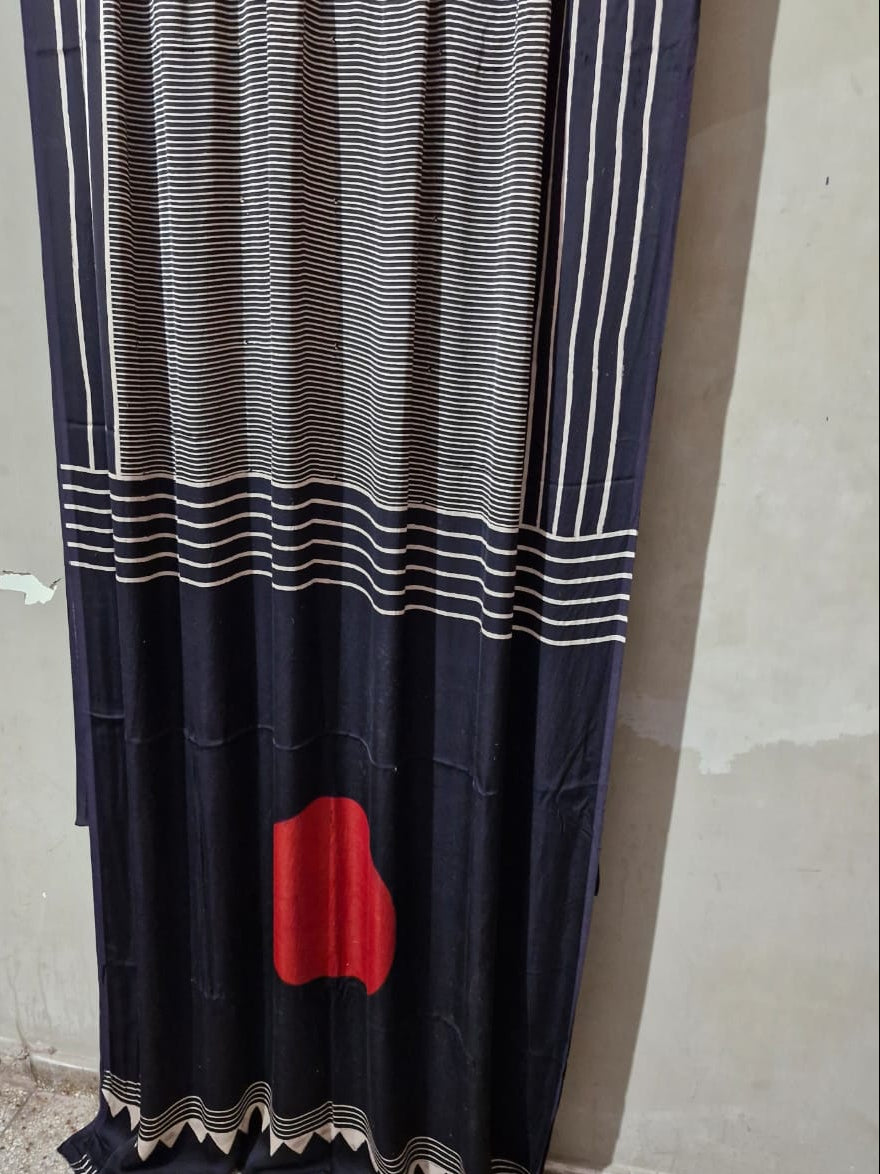 Black and white striped curtain with a red heart design against a plain wall.