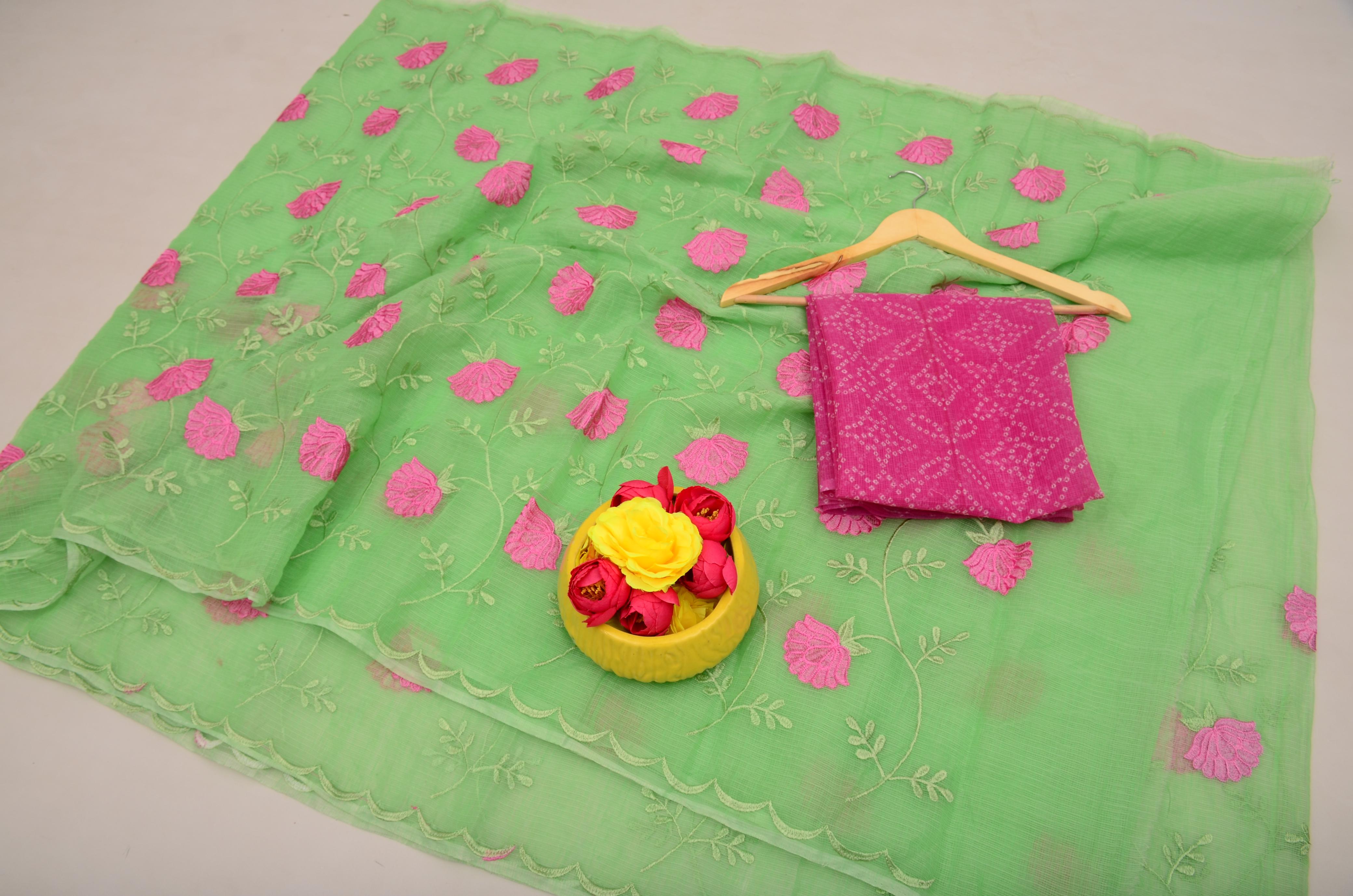 Green fabric with pink floral patterns and a pink garment on a hanger, with a yellow basket of flowers on a white background.