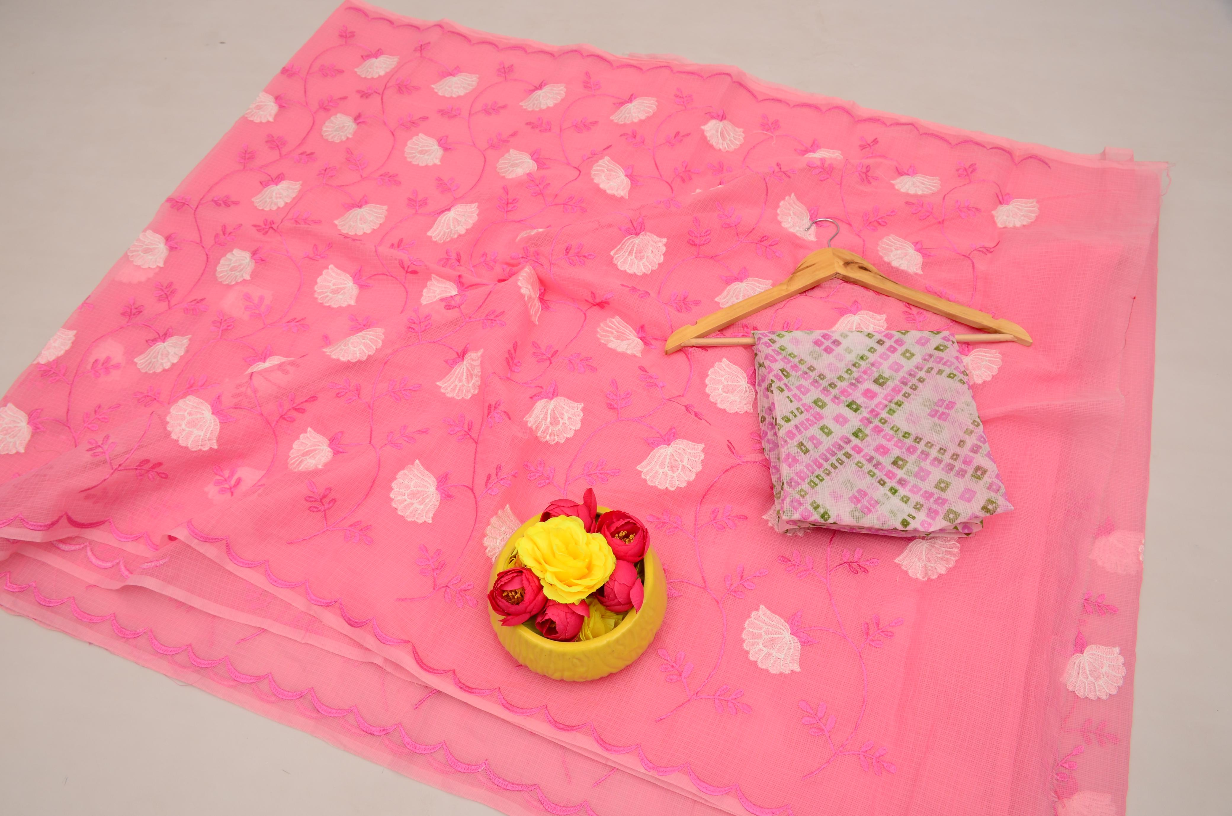 Pink fabric with white leaf pattern, yellow basket with flowers, and folded fabric on a light gray background