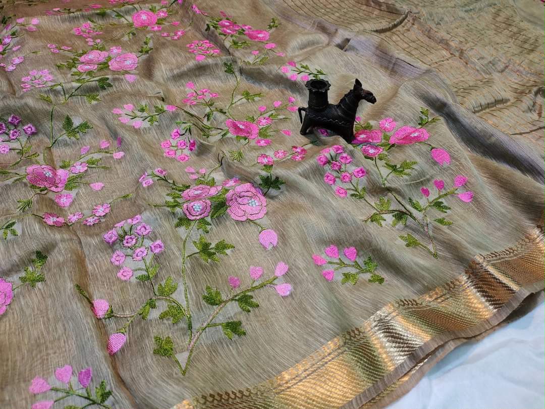 Embroidered fabric with pink flowers and green leaves on a beige background