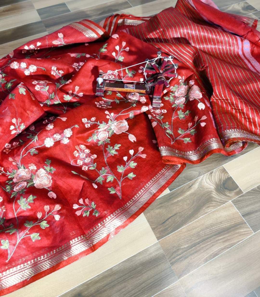 Red saree with floral patterns on a wooden floor