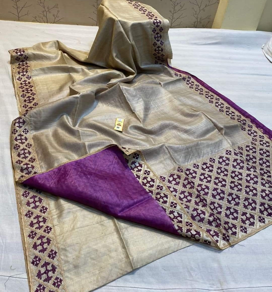 Beige and purple saree with intricate patterns on a white surface