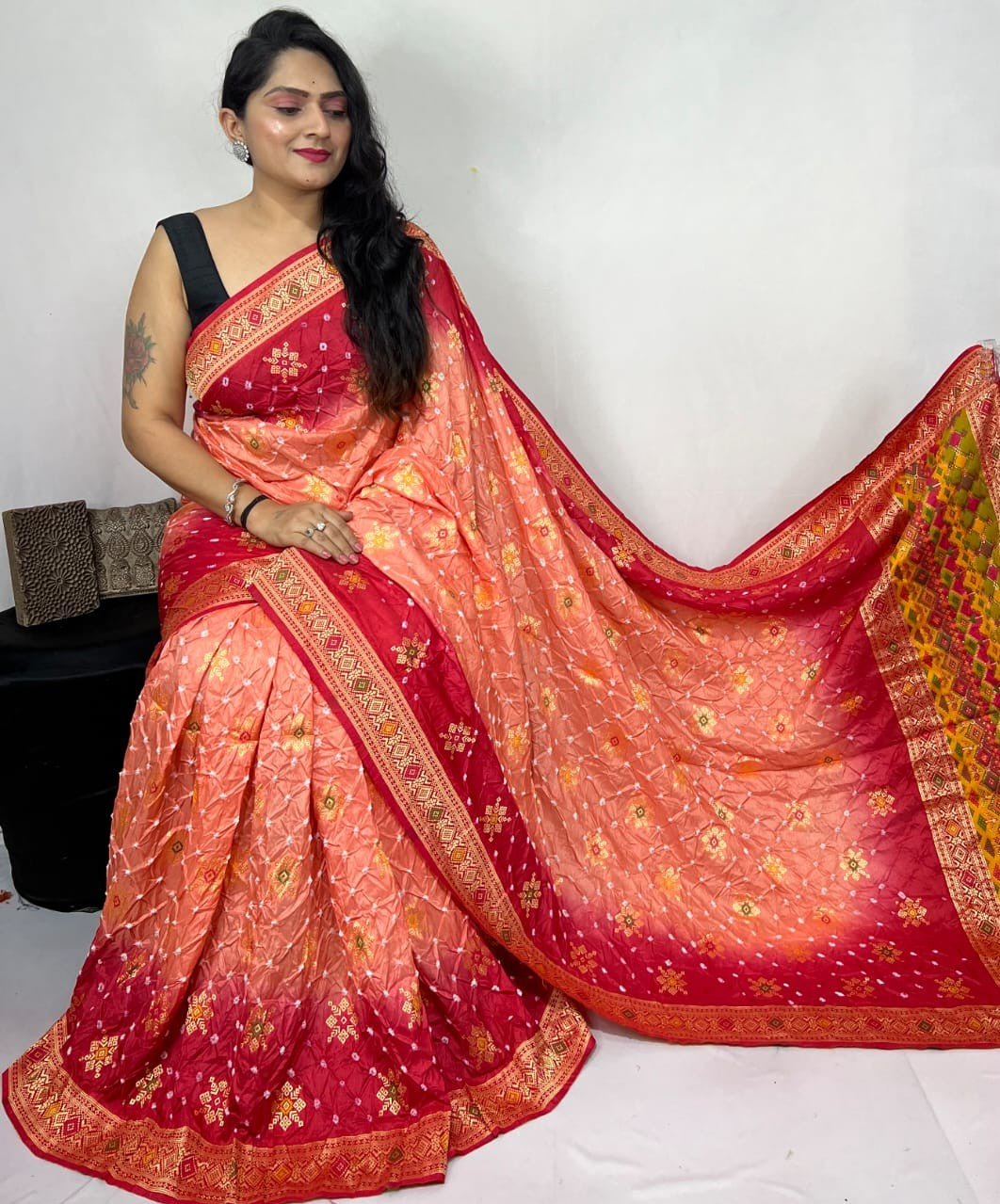 Woman wearing a red and orange saree with a white background