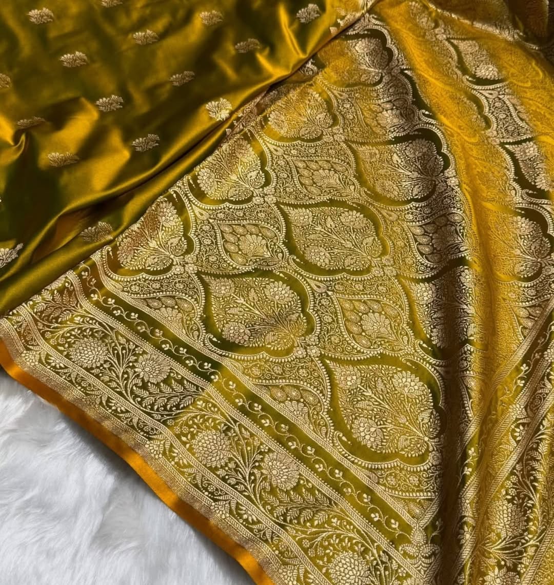 A close-up of an ornate brocade fabric in olive green and gold, featuring intricate metallic floral and paisley patterns with a matching olive green border.
