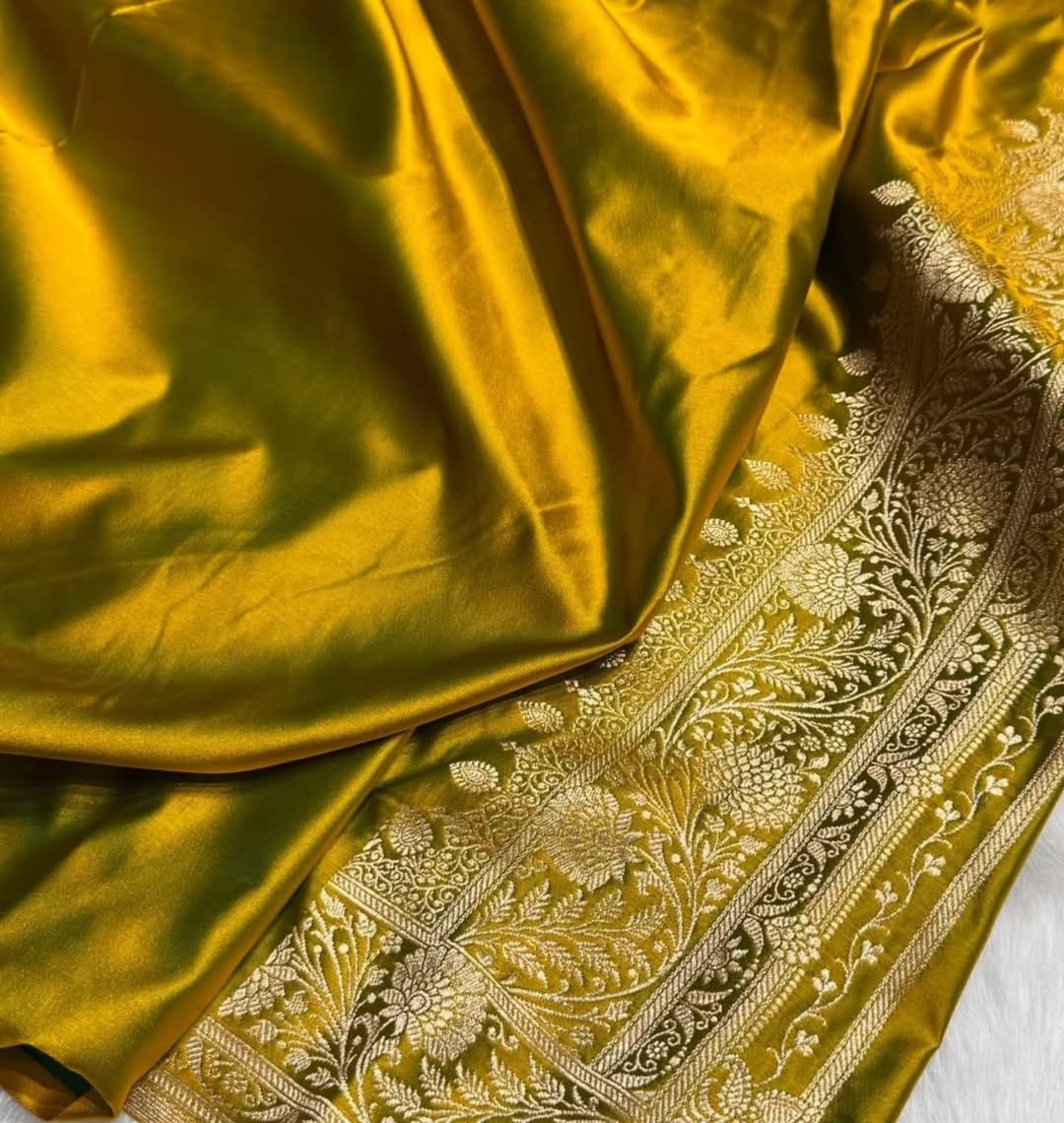 A close-up of a rich olive green silk fabric with an ornate gold and silver floral brocade border.