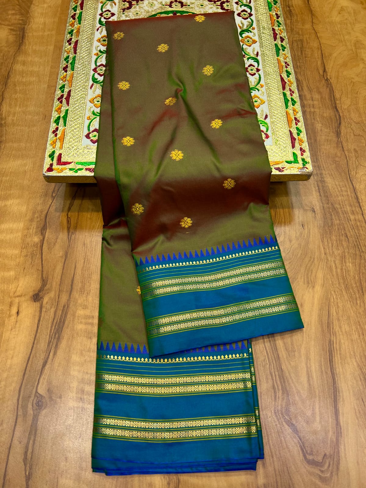 Brown and green saree with blue border on a wooden surface
