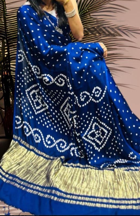 Pure modal silk Bandhani print saree showing traditional dotted motifs and zari pallu edge. A royal blue Bandhani patterned dupatta with a wide gold and silver zari border, draped over a model in an indoor setting.