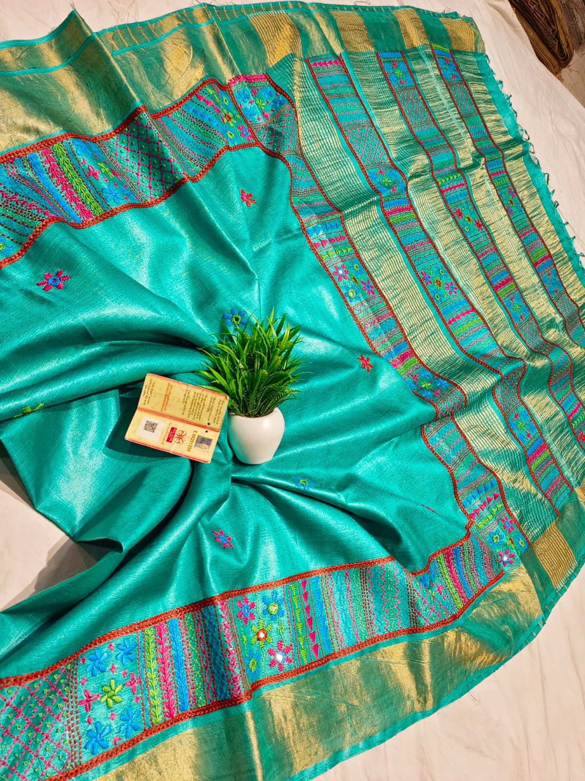 Teal saree with colorful patterns on a bed
