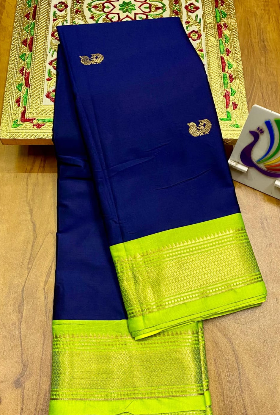 Navy Blue and green saree with a decorative border on a wooden surface