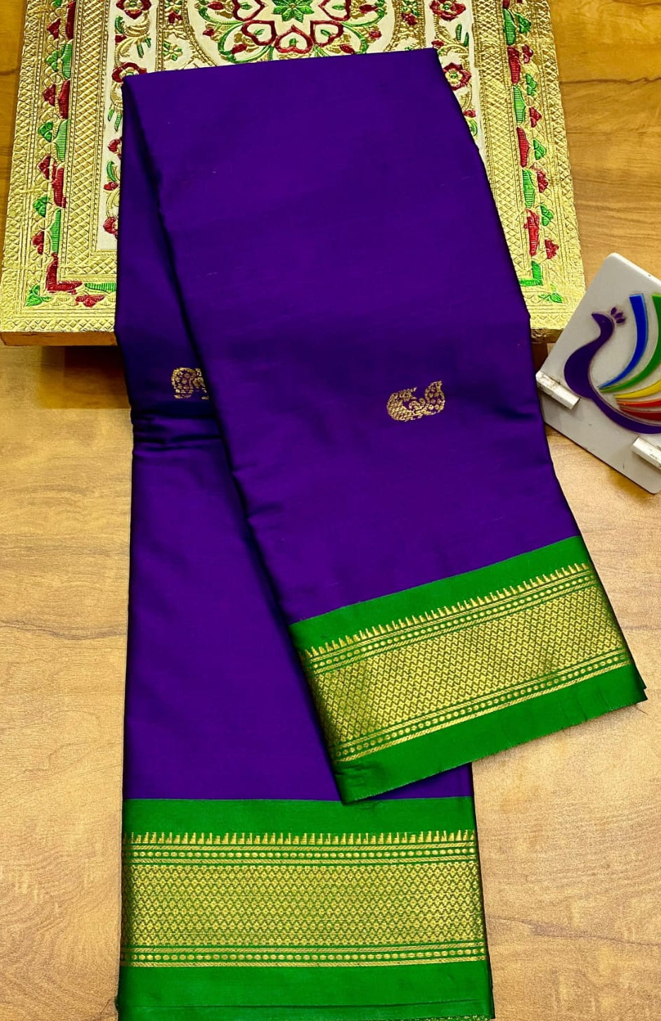 Purple saree with green border on a wooden surface