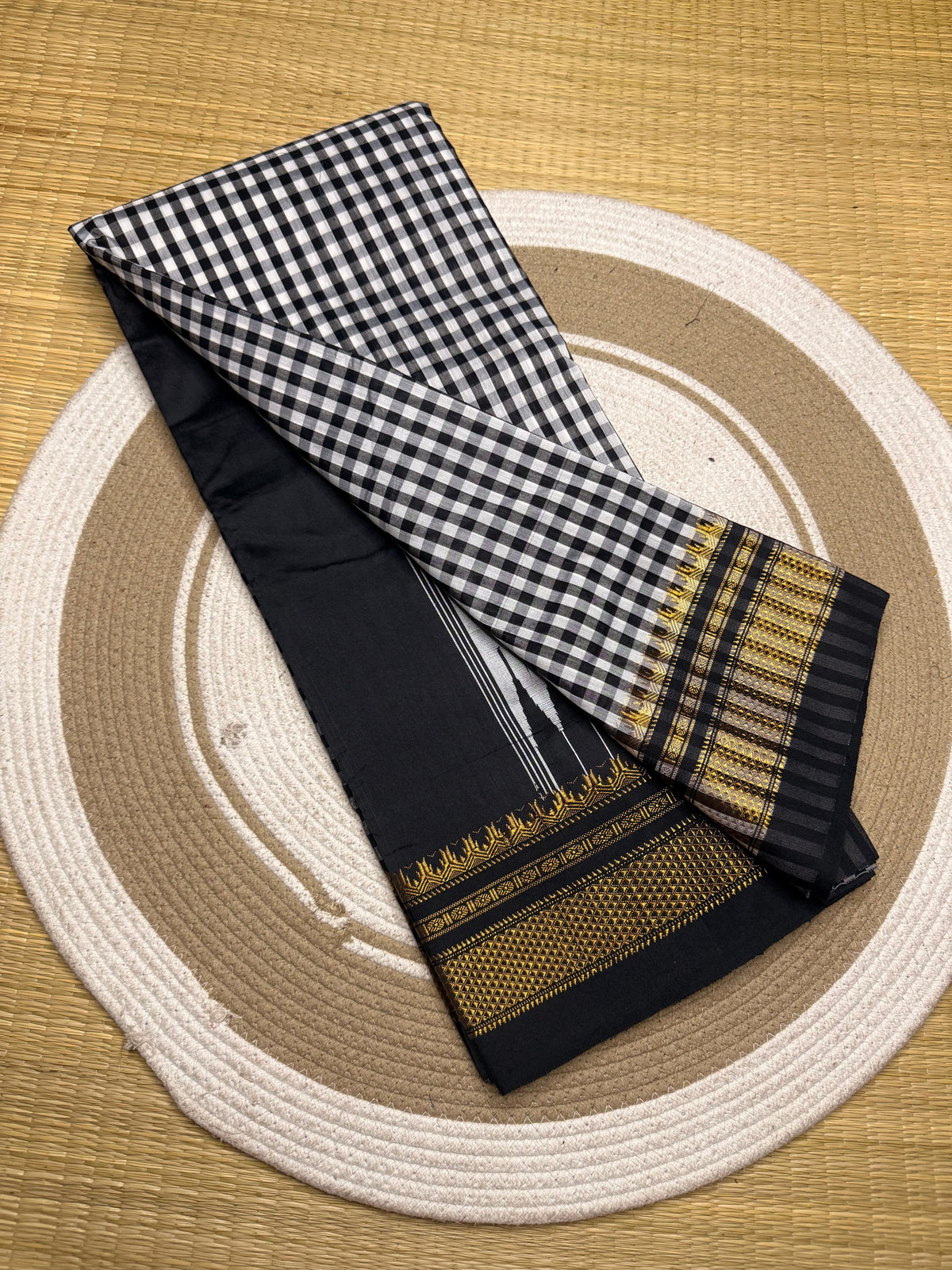 Black and white checkered fabric with gold patterns on a woven mat