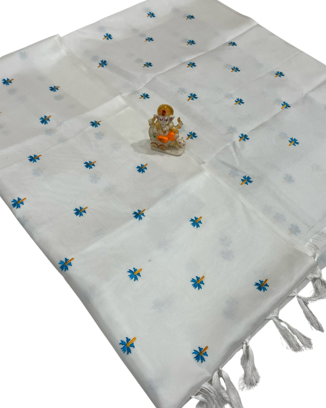 White fabric with blue floral patterns and a small statue on a white background