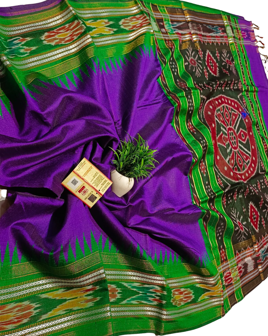 Purple and green saree with intricate patterns, a plant, and a card on a white background