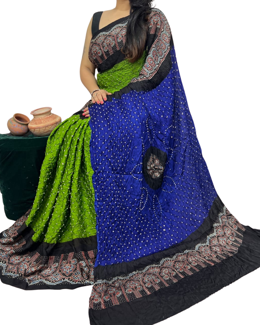 Woman holding a blue saree with green and black patterns on a white background