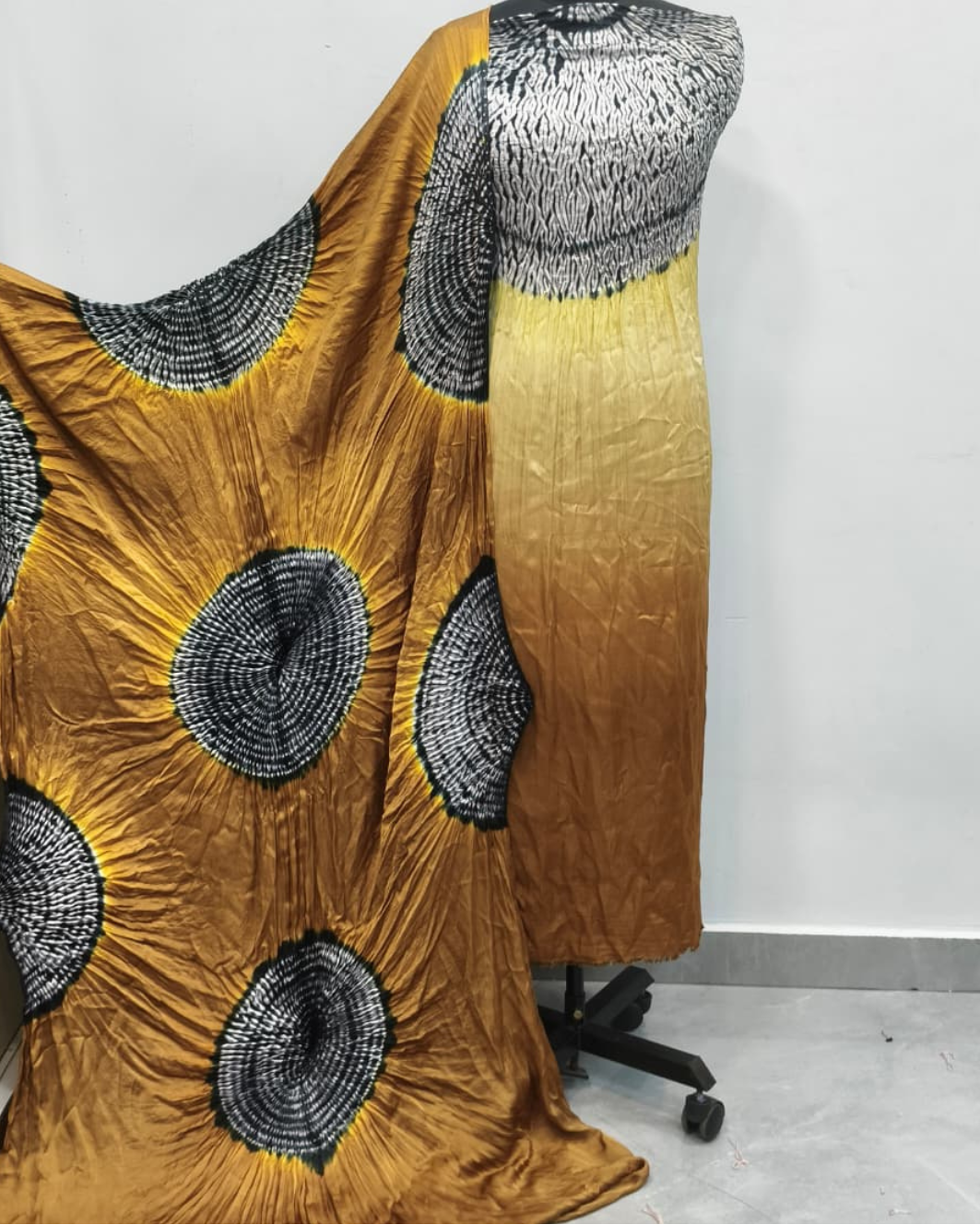 Mustard yellow dress with black circular patterns on a mannequin against a white background