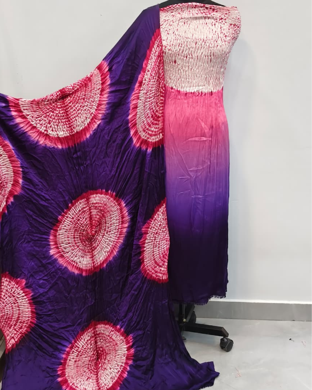 Purple fabric with pink circular patterns on a mannequin against a white background