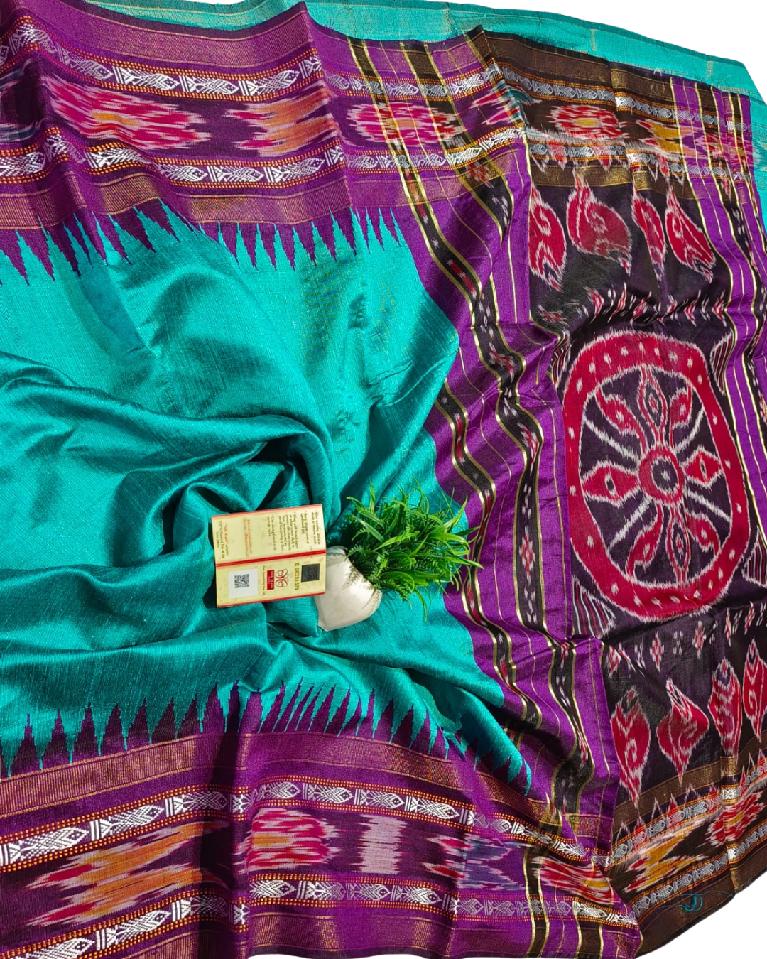 Teal and purple patterned fabric with a small plant and box on top
