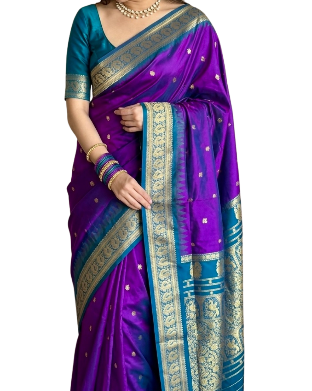 A woman wearing a purple and teal blue silk saree with intricate gold zari woven borders and motifs, paired with a teal blue blouse.