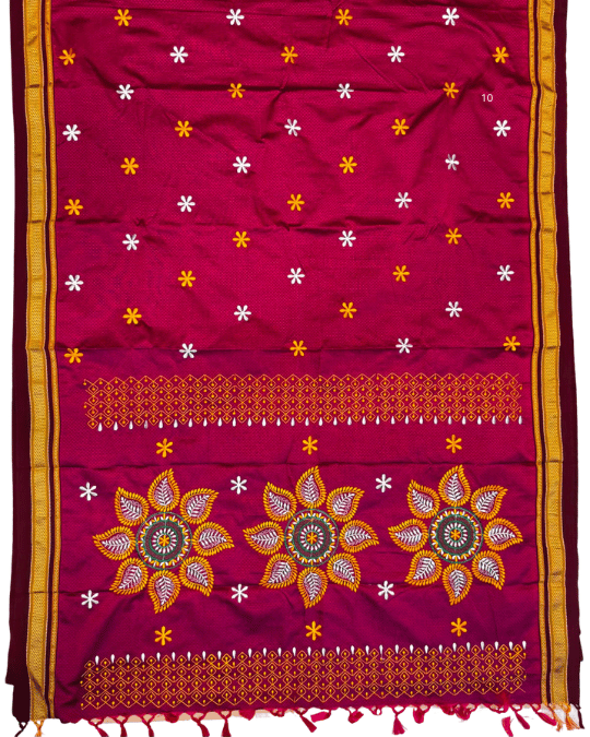A magenta pink fabric textile, likely a traditional sari, featuring embroidered floral motifs, geometric borders, and small star patterns in yellow, white, and orange.