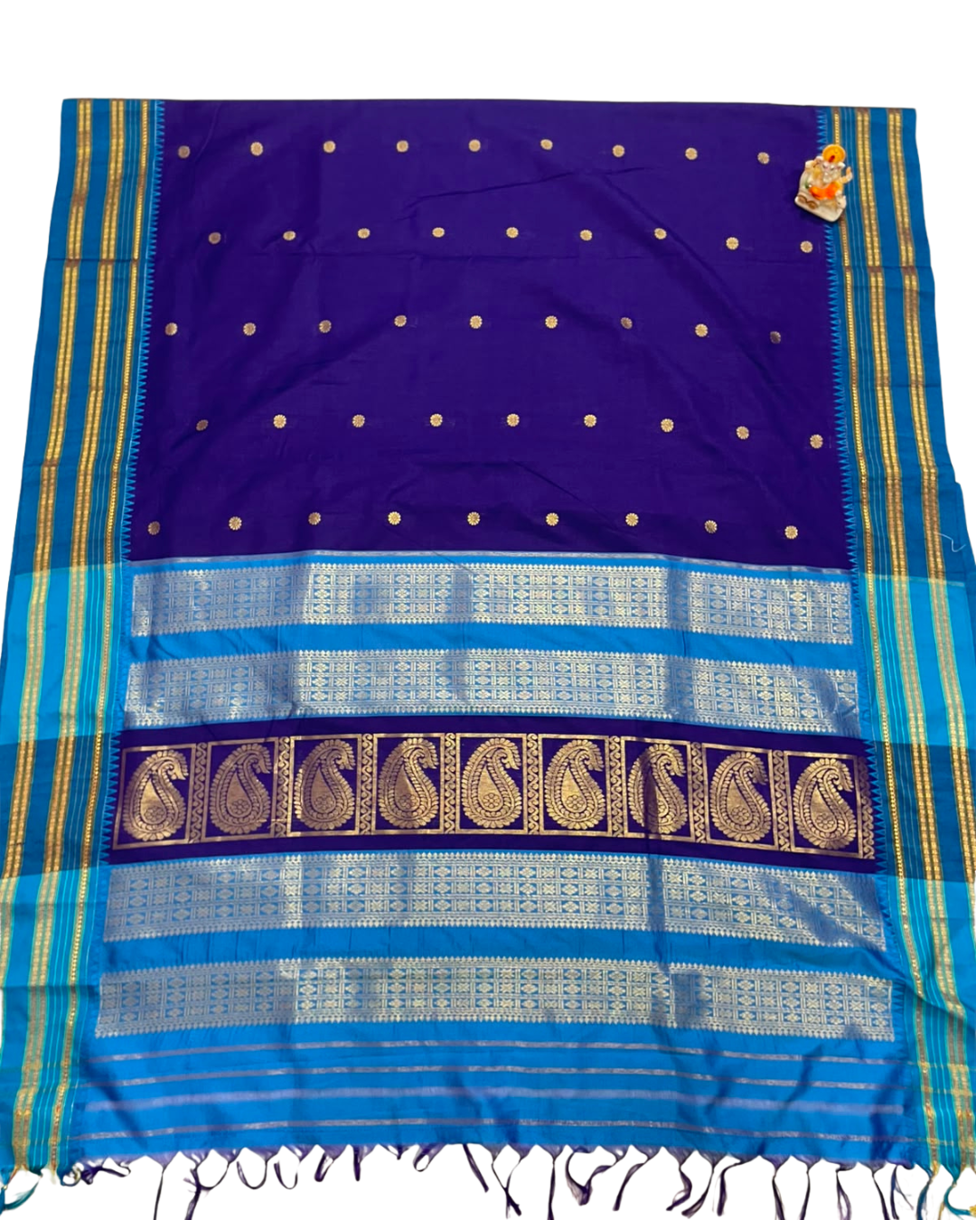 A royal blue and turquoise silk saree with gold zari embroidery, featuring a dotted body, a wide border with paisley motifs, and fringed edges.