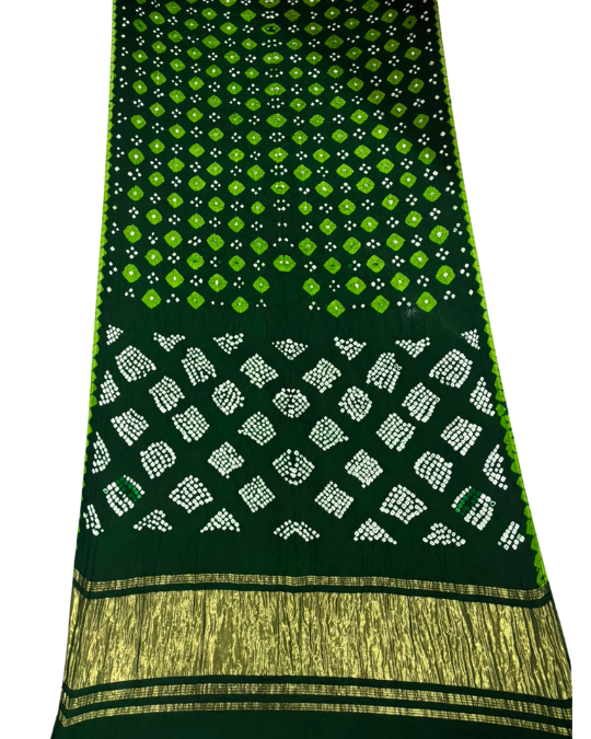 A dark green silk saree with a white and lime green bandhani tie-dye pattern and a gold zari border, displayed flat against a white background.