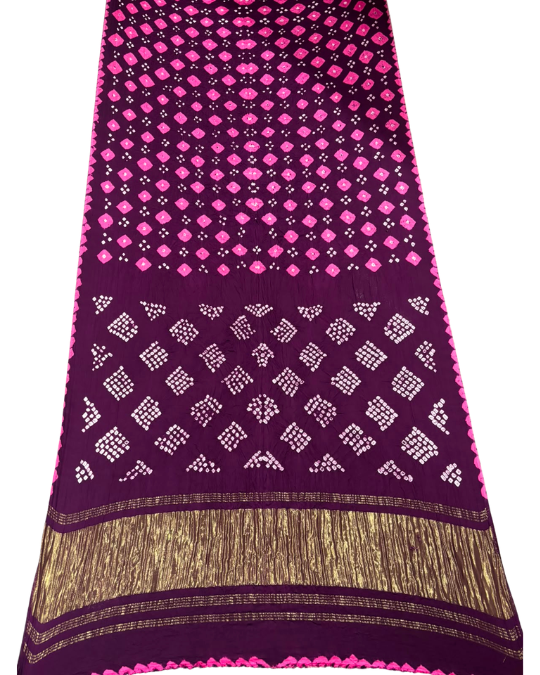 A dark purple silk saree or fabric panel featuring vibrant pink and white ikat bandhani patterns, with a wide gold zari border and fringe along the bottom.
